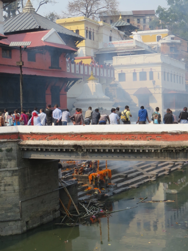 Bystanders filled the bridge near the ghat where the high official was being cremated.