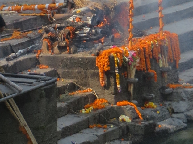The body was wrapped and laid upon the cremation pyre.  Then family and friends passed by, laying garlands of flowers on top. 