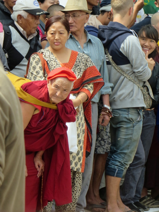 This little nun, dressed in red, could hardly wait for the Dalai Lama to appear.